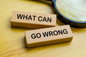 Top view of What Can Go Wrong text on wooden blocks with magnifying glass. Auditing concept.