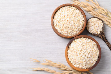 Oat flakes in wooden bowl and spoon on white background with copy space, Food ingredient in oatmeal, muesli or porridge