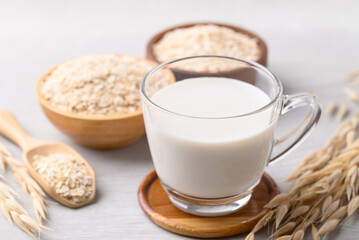 Oat milk in cup glass with oat flakes on white background, Alternative milk made from plant, non dairy