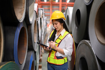 engineer woman inspecting and checking store at warehouse of steel role material. smart industry worker operating. Industry maintenance engineer woman with metal sheet at factory.