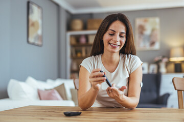 Smiling Woman Checking Blood Sugar Level at Home with Glucometer