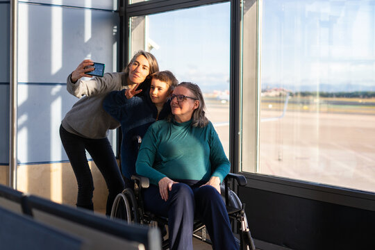 Family taking selfie at airport with grandmother in wheelchair