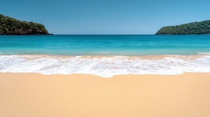 Obraz premium Soft waves lap a pristine sandy beach, framed by lush green hills under a vibrant blue sky.