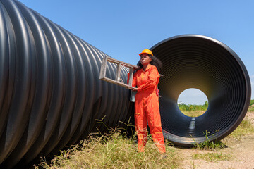 A black female mechanical engineer in a safety uniform inspects and inspects piping systems for a...