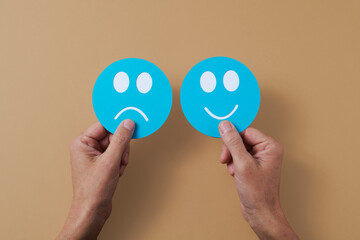 holding a sad face and a happy face in his hands