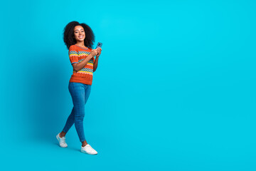 Full body length photo of walking girl using smartphone for job content manager advertising instagram store isolated on blue color background © deagreez