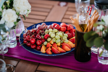 Fresh fruit platter with strawberries, grapes, and peaches on table, perfect for summer events