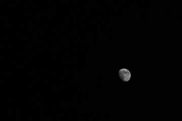 A captivating view of a waxing moon in the dark night sky. The image showcases the moon’s...