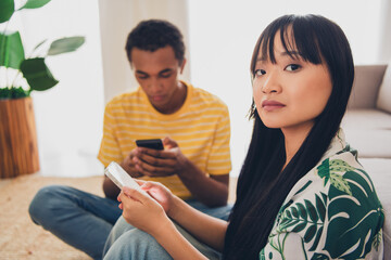 Photo of bad mood sad young couple wife husband sitting separate social media post indoors flat apartment