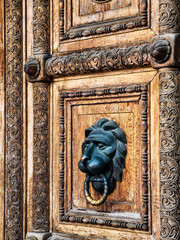 Intricate wooden door featuring a detailed lion head knocker