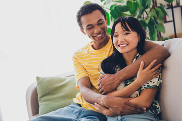 Photo of cheerful positive sweet people wear t-shirts sit couch vacation together romantic time indoors living room