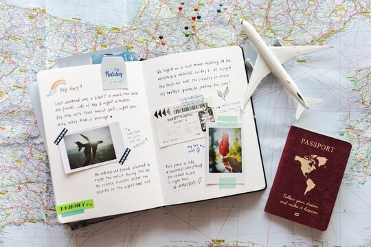 Travel journal with maps, passport, and airplane model. Open notebook with travel notes, photos, and tickets. Travel planning journal flat lay photo. World map with travel journal and airplane model