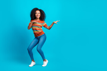 Full body length photo of dancing young relaxed american girl in stylish t shirt chill discotheque active rhythm isolated on blue color background