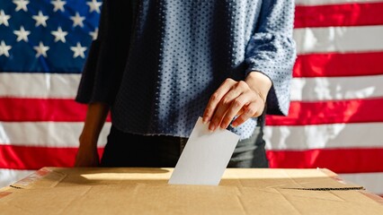 Person placing ballot into voting box at American election with American flags. Ballot and voting...