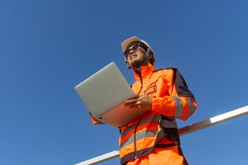 Asian engineer advance technology technician mechanic male standing with laptop computer on blue sky
