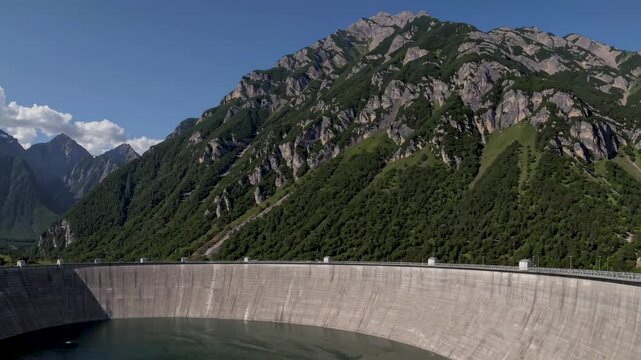 Vajont dam stands tall, showcasing its impressive structure against a backdrop of lush green mountains and a serene water reservoir, creating a picturesque scene of nature and engineering