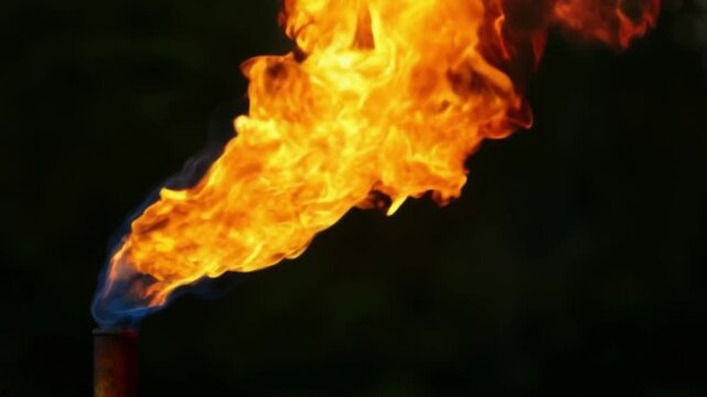 Bright flames erupt from a pipe as oil is being processed in an industrial oil production facility
