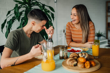 Lesbian couple enjoying breakfast and laughing together at home