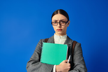 A young woman stands confidently with a notepad and pen, conveying a strong emotional presence.