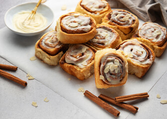 Freshly baked cinnamon rolls topped with cream cheese frosting and almond slivers