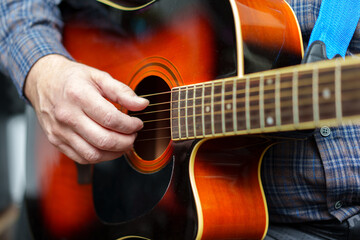 A man plays an acoustic guitar in close-up.