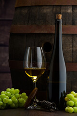 Glass of wine, cheeses and grapes on old wooden table. dark background.