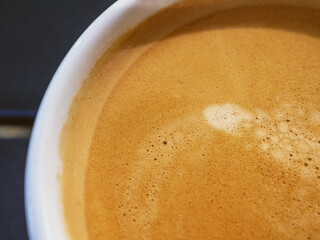 Coffee cream texture of fragrant coffee in a cup with delightful coffee colored bubbles with foam. macro coffee crema