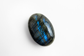 Oval shape blue and black color Labradorite gemstone on white background. Lot of copy space.

