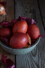 Boiled eggs dyed with onion peel in a bowl on a wooden background.