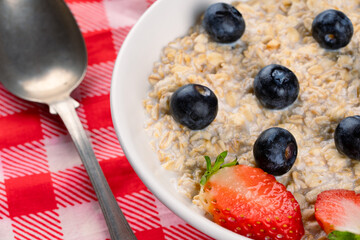 Milk porridge prepared for breakfast with blueberries, strawberries and bananas