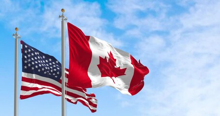 Canada and american national flags waving in the wind on a clear day