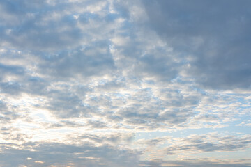 Fototapeta premium The fluffy white clouds drift across the blue summer sky, a breathtaking cloudscape against the vast expanse of heaven