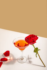 Glass of red wine with red rose on the white background. Romantic date concept.