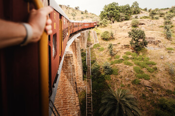 Hand hält sich an einem Handgriff an einem offenen Zug, der durch Rajasthan Indien fährt