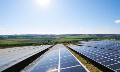 a solar farm with rows of solar panels glistening under the bright sun. In the foreground a modern sprinkler system