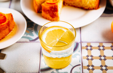 Glass of fresh lemonade and orange cake with fruit citrus slices.