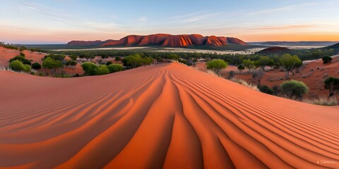 Fototapeta premium A vast desert landscape featuring red sand dunes and distant rocky formations under a colorful sky at sunrise. Concept Desert Sunrise, Red Sand Dunes, Rocky Formations, Colorful Sky, Vast Landscapes