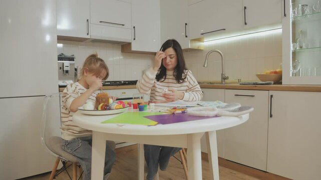 Young beautiful mother and charming daughter are painting Easter eggs. Mom and daughter are getting ready to celebrate Easter. Celebrating Easter with family.