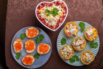 Salad with pomegranate in a heart-shaped salad bowl next to tartlets