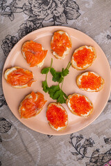 Canapes with red caviar and salted salmon on a plate decorated