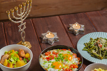 Set table, Jewish food, tzimmes, chelnt, shakshuka and couscous with dried fruits