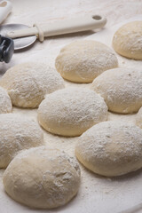 Massa de pão e pizza espelhadas com farinha, tudo numa mesa de pizzaollo