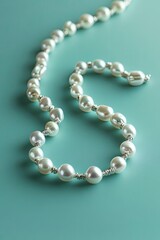 Obraz premium minimalist flat lay of pearl necklace arranged in flowing lines on matte turquoise background