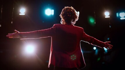 Leader performing on stage, back view, mixed race man speaking and chatting. Charismatic male person standing against bright soffits, silhouette, rearview, life coach talking motivational speech