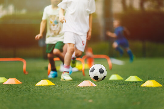 Young Boy Running With Soccer Ball Through Training Obstacle Course. Group of School Kids on Sports Outdoor Training. Children Practicing Football On Summer Day
