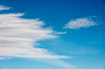 Fototapeta premium Blue sky with soft, wispy white clouds stretching across, creating a peaceful and serene natural scene.
