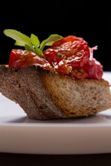 Bruscheta ou torrada ou pão com azeite salame e tomate, uma massa no prato branco