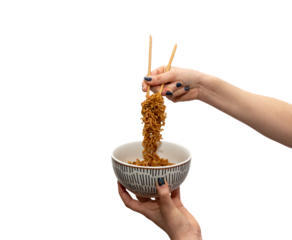 Close-up of a woman's hands holding a porcelain bowl with one hand and with the other one holding delicious Chinese noodles, ramen, with chopsticks on a white background.