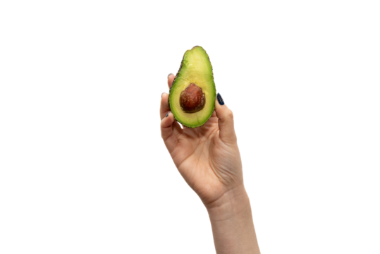 Close-up of a woman's hand holding a halved avocado with the pit exposed against a white background.