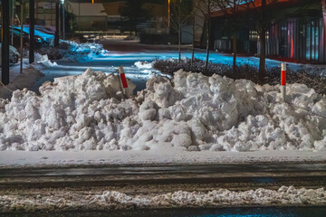 winter in the city, sudden attack of winter at night in the city. a pile of snow lying on the edge...